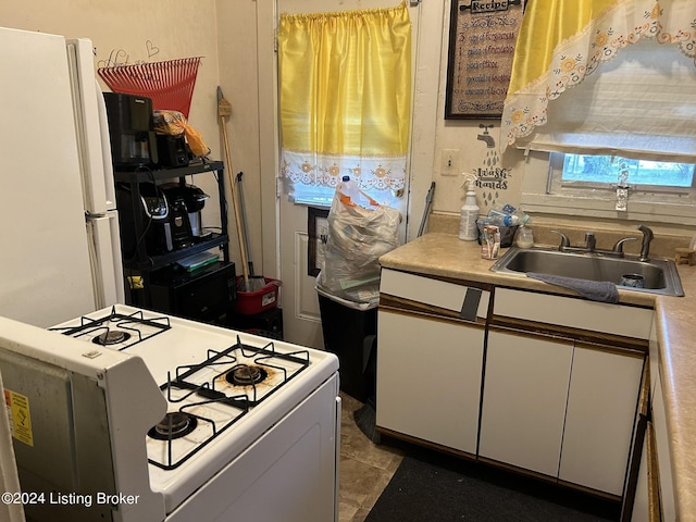 kitchen featuring light countertops, white appliances, white cabinetry, and a sink