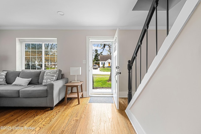 foyer entrance featuring stairway, light wood finished floors, baseboards, and ornamental molding