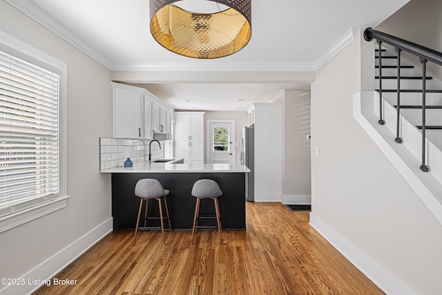 kitchen featuring crown molding, a sink, white cabinetry, and a breakfast bar