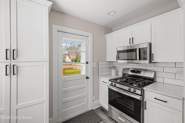 kitchen with stainless steel appliances, light countertops, white cabinetry, and decorative backsplash