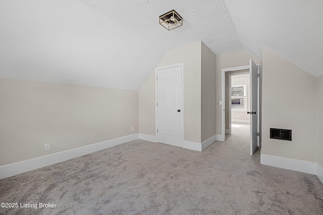 bonus room featuring visible vents, baseboards, a textured ceiling, vaulted ceiling, and carpet flooring