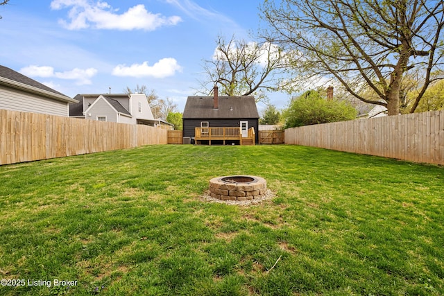 view of yard featuring a fenced backyard, a wooden deck, and a fire pit