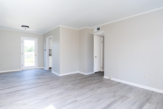 empty room with crown molding, light wood finished floors, visible vents, and baseboards