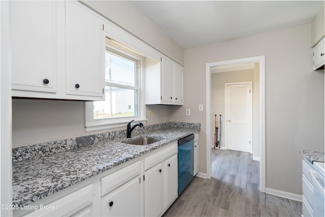 kitchen with baseboards, white cabinets, a sink, and dishwashing machine