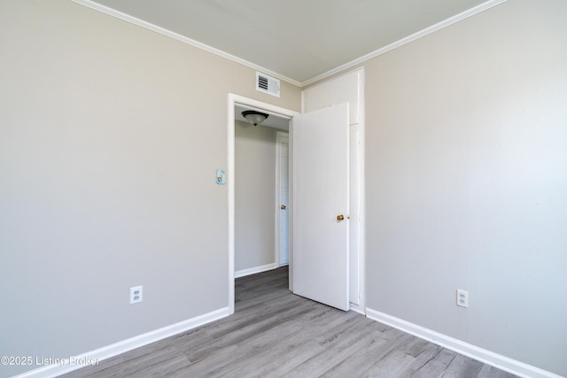 unfurnished bedroom featuring ornamental molding, visible vents, baseboards, and wood finished floors