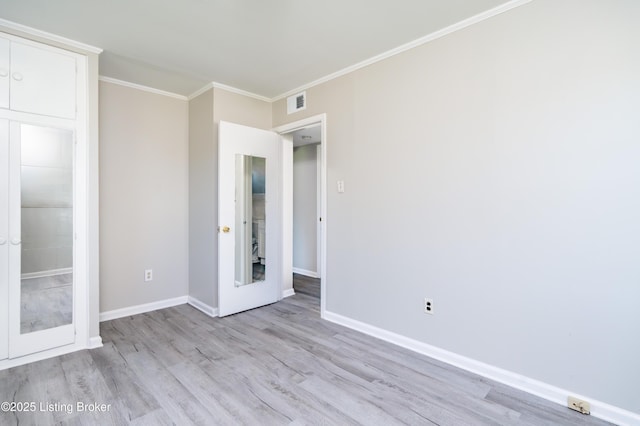 unfurnished bedroom with ornamental molding, wood finished floors, visible vents, and baseboards