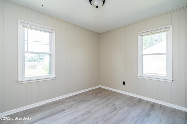 empty room with a healthy amount of sunlight, light wood-style flooring, and baseboards