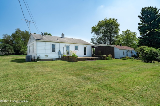 rear view of property with a lawn, a chimney, and central air condition unit