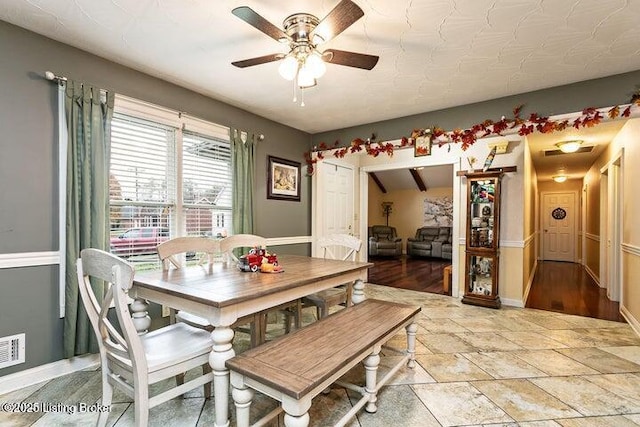 dining area with ceiling fan, baseboards, and stone tile floors