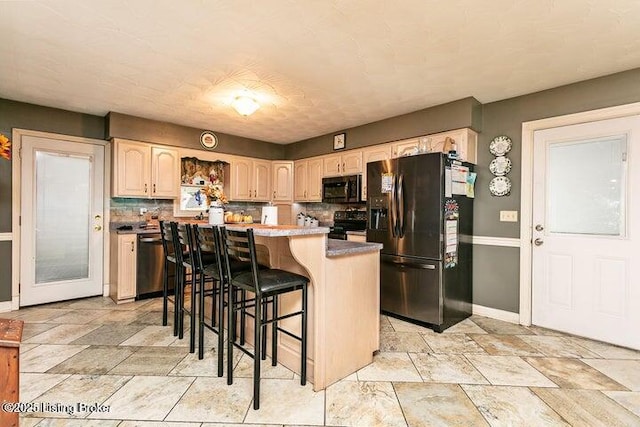 kitchen featuring baseboards, a breakfast bar, a center island, black appliances, and backsplash