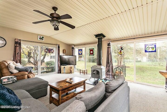 living room with carpet floors, a wood stove, ceiling fan, and lofted ceiling