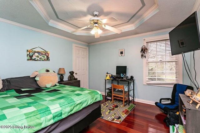 bedroom with a raised ceiling, ornamental molding, a ceiling fan, wood finished floors, and baseboards