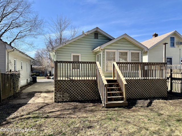 rear view of house featuring a deck and fence