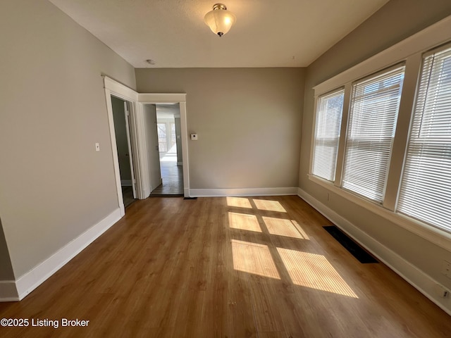 spare room with visible vents, baseboards, and wood finished floors