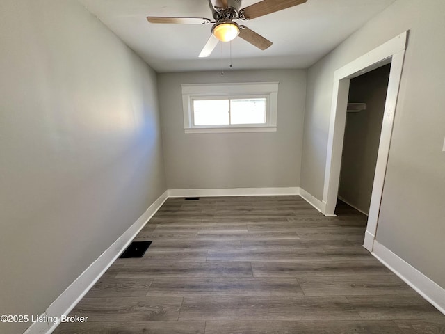 unfurnished bedroom with dark wood-style floors, ceiling fan, visible vents, and baseboards