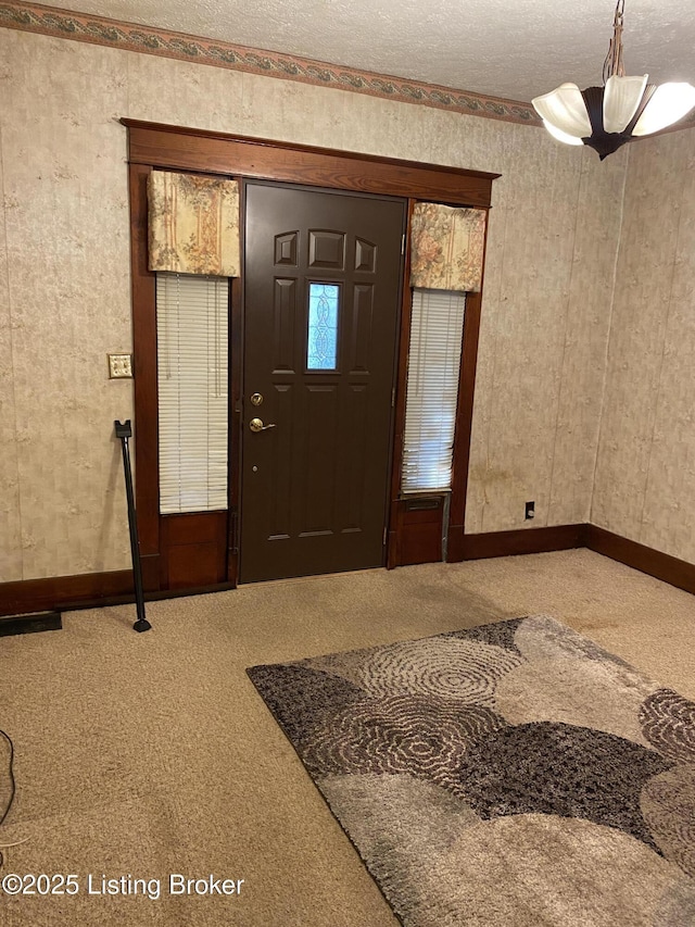 carpeted entrance foyer with a textured ceiling and baseboards