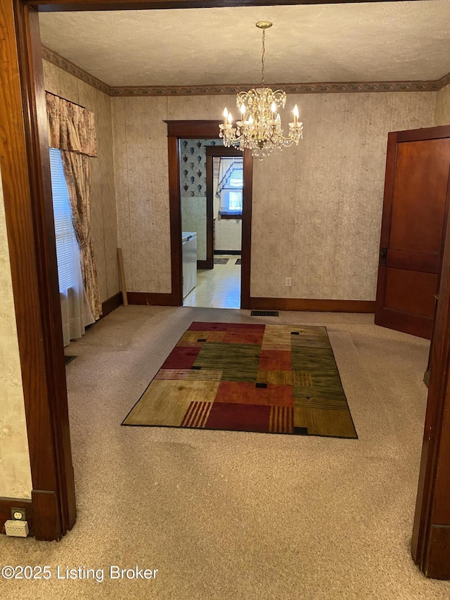 unfurnished dining area with visible vents, a notable chandelier, a textured ceiling, and wallpapered walls