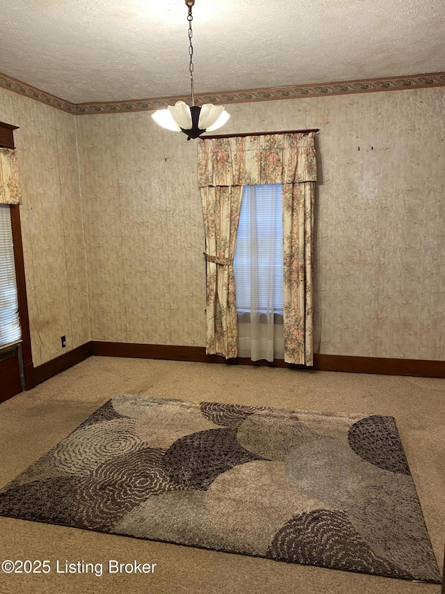 empty room with a notable chandelier, a textured ceiling, baseboards, and carpet flooring