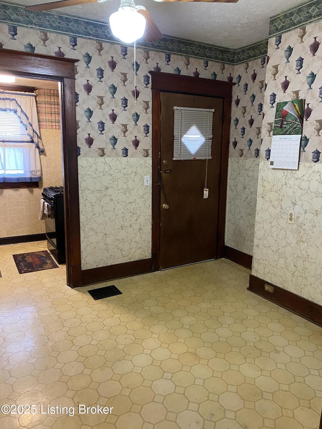 entryway with wallpapered walls, baseboards, visible vents, and a textured ceiling