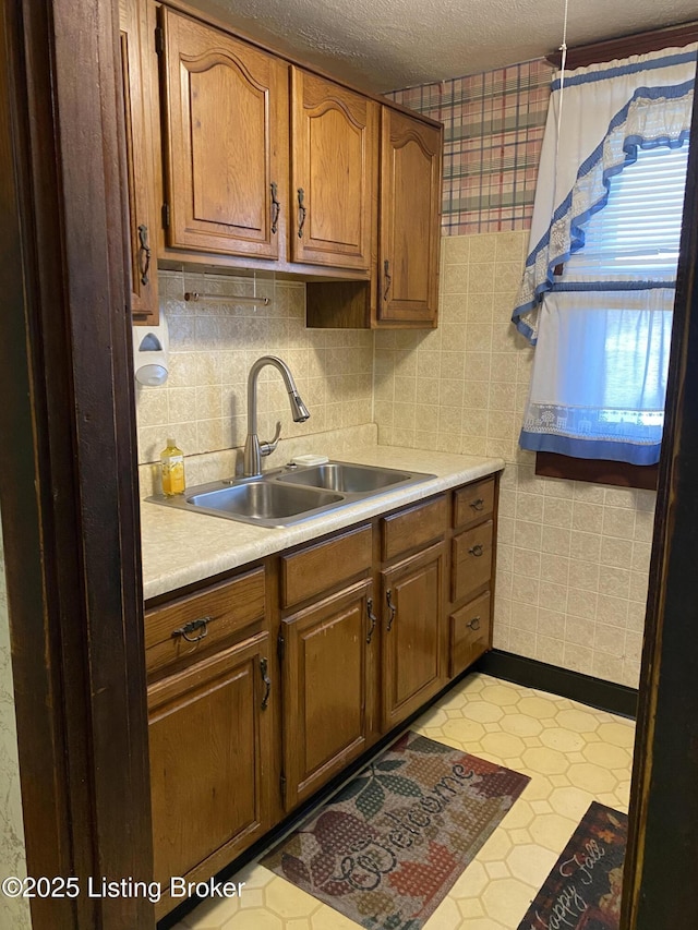 kitchen with brown cabinets, light countertops, a sink, and a textured ceiling