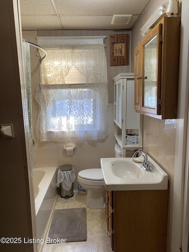 full bath with a paneled ceiling, vanity, toilet, and shower / bath combo with shower curtain