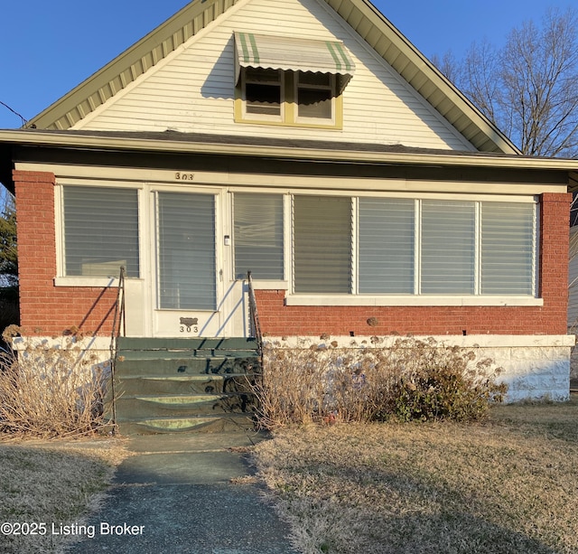 bungalow featuring brick siding