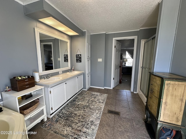 full bath with double vanity, visible vents, a sink, a textured ceiling, and a shower stall