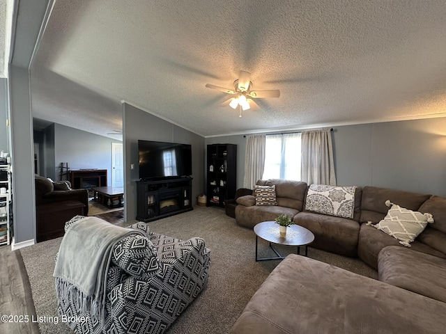 carpeted living area with a ceiling fan, lofted ceiling, a fireplace, and a textured ceiling