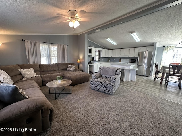 living room featuring ceiling fan, a textured ceiling, light colored carpet, light wood-style floors, and vaulted ceiling