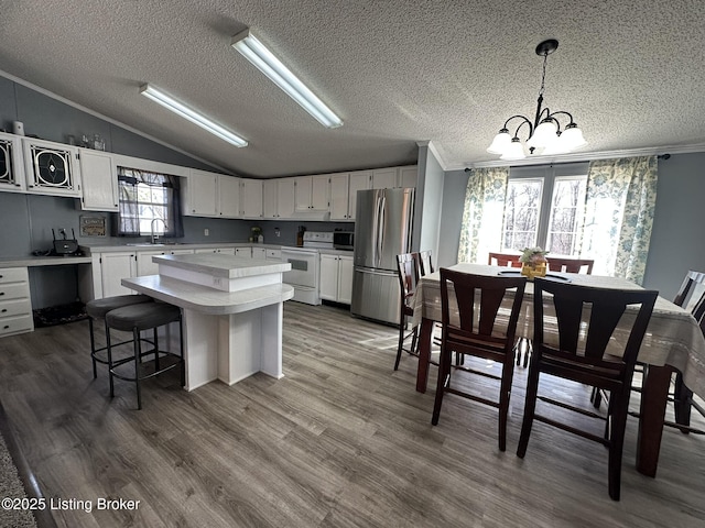 kitchen featuring electric stove, lofted ceiling, light countertops, freestanding refrigerator, and a sink