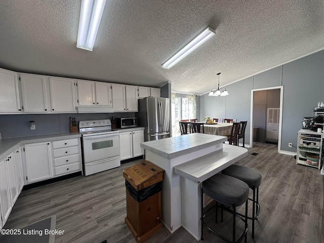 kitchen with lofted ceiling, white cabinetry, stainless steel appliances, and dark wood finished floors