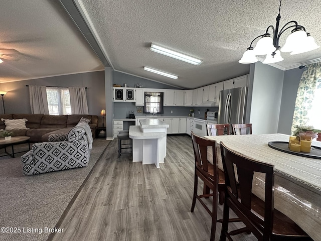 kitchen featuring open floor plan, freestanding refrigerator, light countertops, white electric range, and a sink