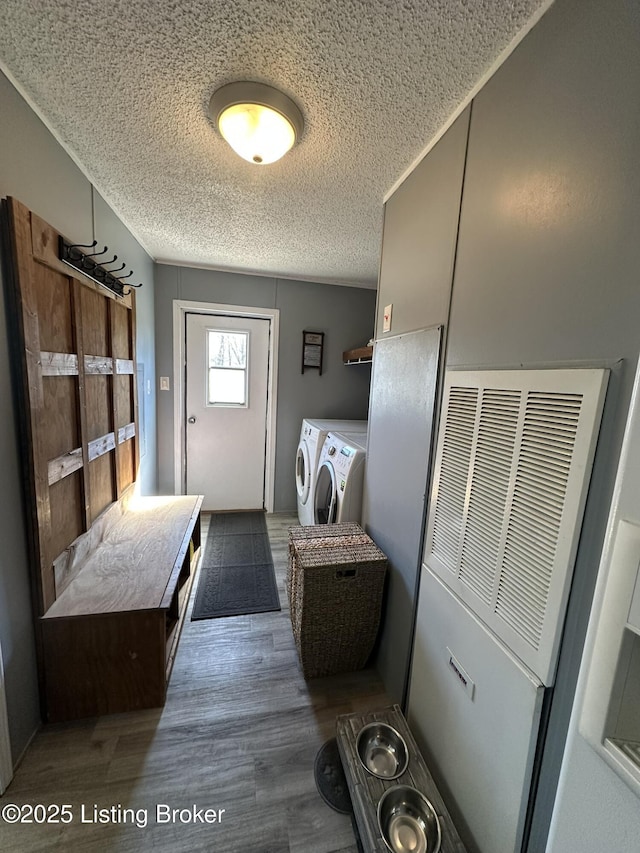 mudroom with a textured ceiling, wood finished floors, and independent washer and dryer