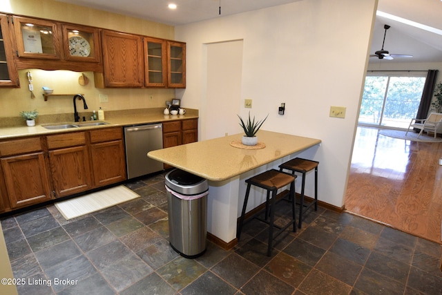 kitchen with stone tile floors, a sink, light countertops, brown cabinets, and dishwasher