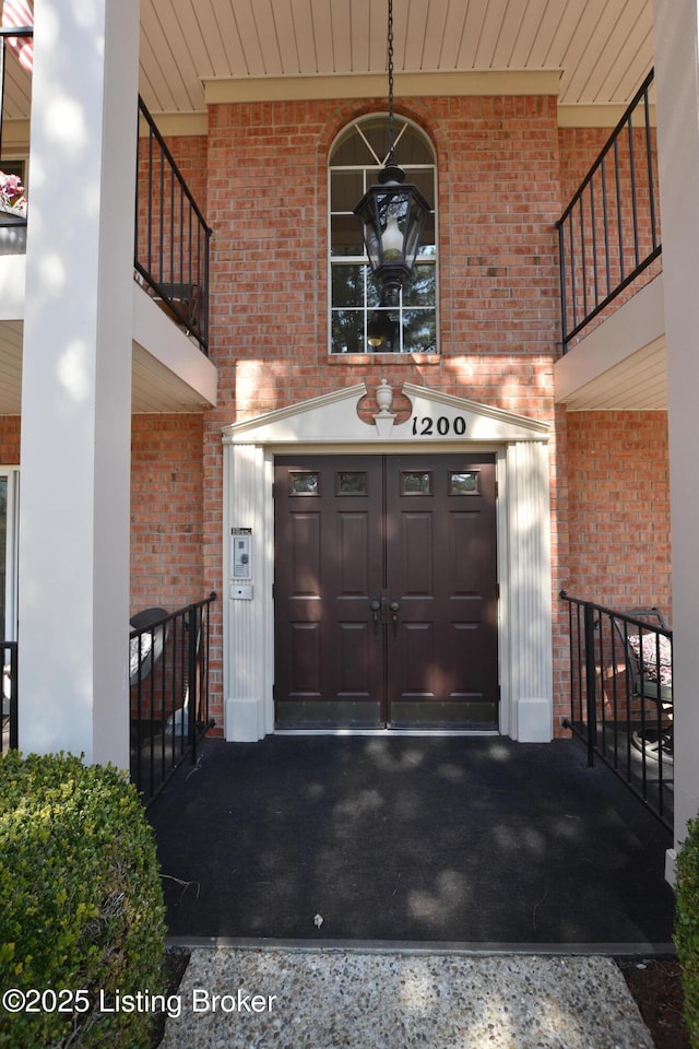 property entrance featuring a garage, brick siding, and a balcony