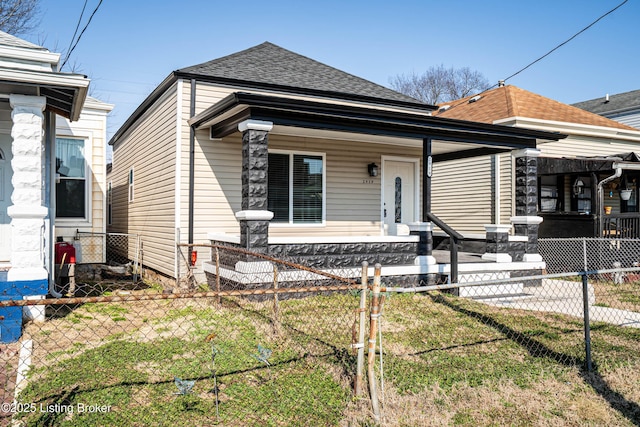 view of front of house with a fenced front yard, covered porch, and roof with shingles