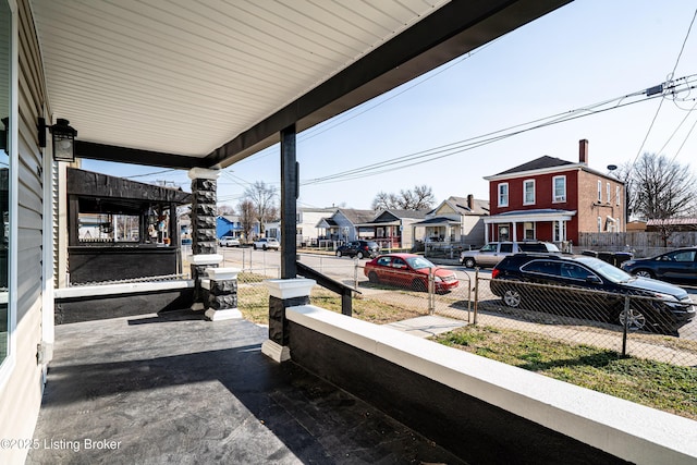 view of patio with a porch, fence, and a residential view