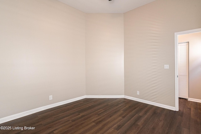 spare room with baseboards and dark wood-style flooring