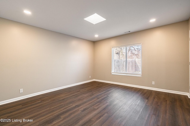 unfurnished room with visible vents, baseboards, a skylight, and dark wood finished floors