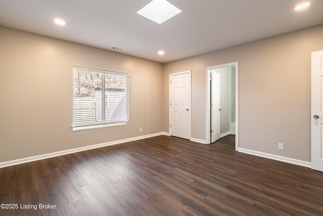 spare room with visible vents, baseboards, a skylight, and dark wood-style flooring