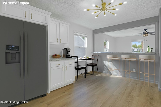 kitchen with fridge with ice dispenser, white cabinets, light wood-style flooring, and a wealth of natural light