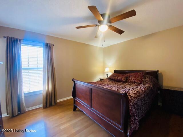 bedroom featuring light wood-type flooring, baseboards, and a ceiling fan