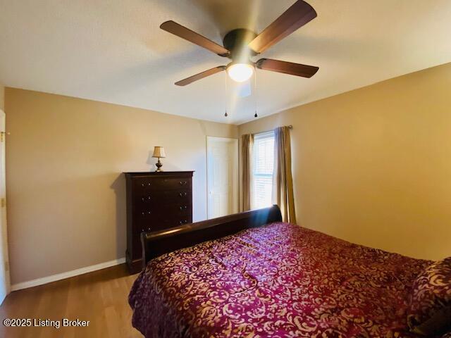 bedroom with a ceiling fan, baseboards, and wood finished floors