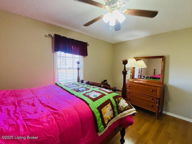 bedroom with a ceiling fan, wood finished floors, and baseboards