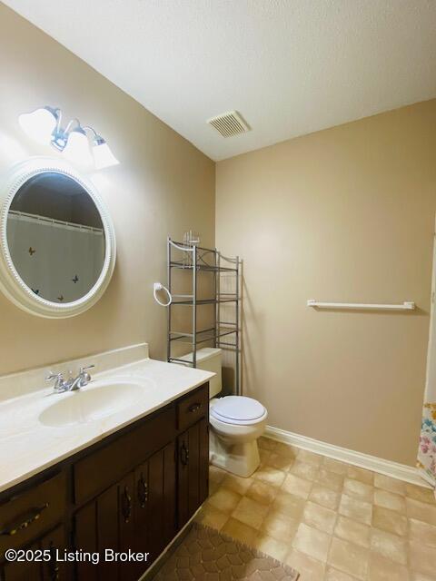 bathroom with vanity, toilet, baseboards, and visible vents