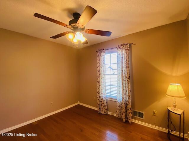 spare room with visible vents, ceiling fan, baseboards, and dark wood-style flooring