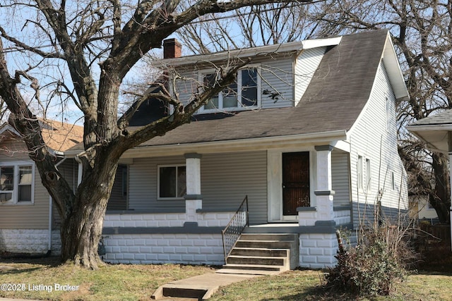 view of front of property with a porch, a chimney, and a shingled roof