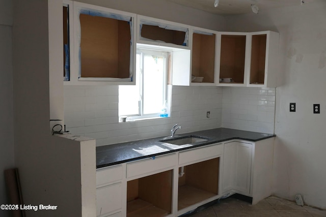 kitchen with dark countertops, decorative backsplash, tile patterned flooring, and a sink