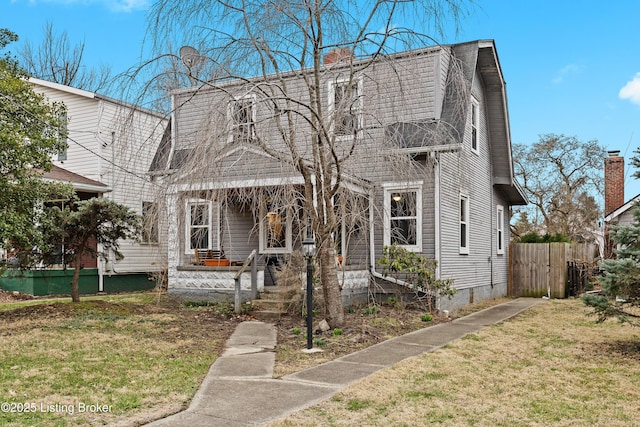 view of front facade with a gambrel roof, a front lawn, and fence