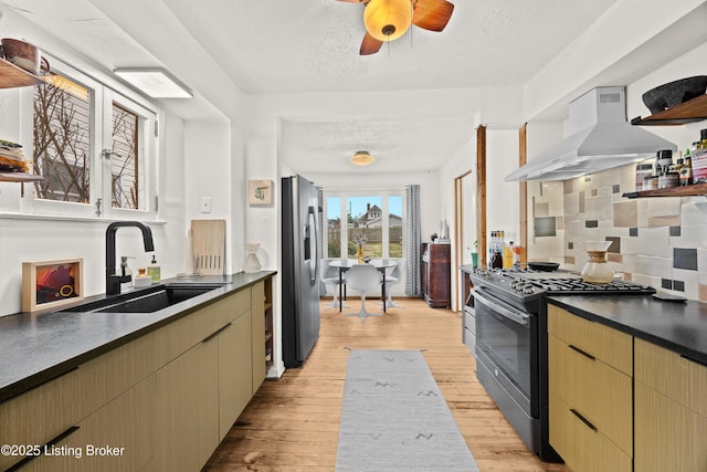 kitchen featuring dark countertops, a sink, ventilation hood, appliances with stainless steel finishes, and open shelves